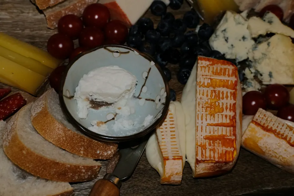 Olika ostar, bröd och frukt på en träbricka