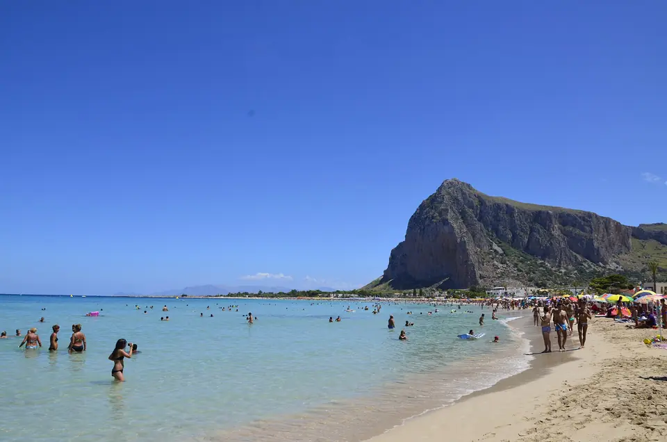 Sandstrand med badande och Monte Monaco i bakgrunden vid San Vito Lo Capo