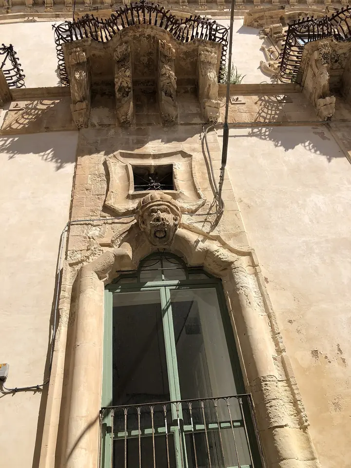 Snidad stenutsmyckning under en balkong på Palazzo Beneventano i Scicli