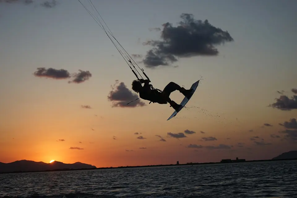 En kitesurfare hoppar över vattnet vid Lo Stagnone med solnedgång bakom