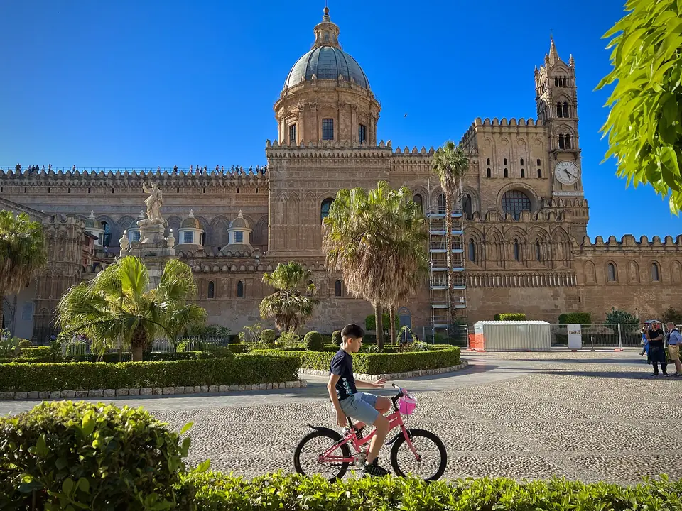 En cyklist på en rosa cykel framför Palermos katedral, som illustration till cykling på Sicilien
