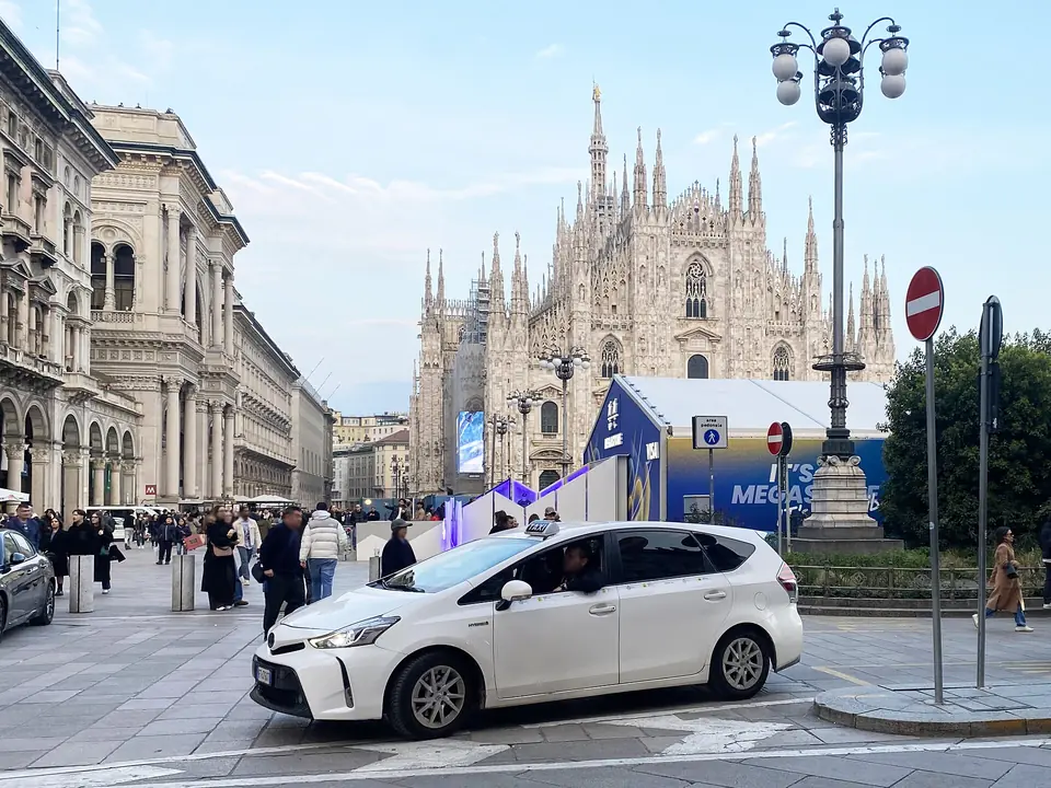 En vit taxi framför katedralen i Milano – illustrationsfoto från italienska fastlandet, utanför Sicilien.