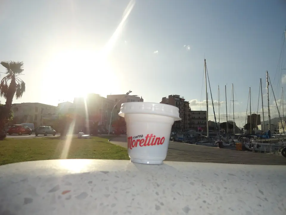 En kaffekopp vid hamnen La Cala i Palermo i lågt solljus.