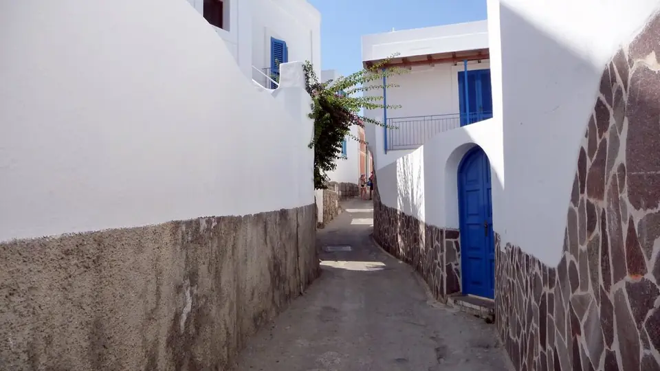 En smal gränd med bostadshus på Panarea – miljöbild, inte ett aktuellt försäljningsobjekt.