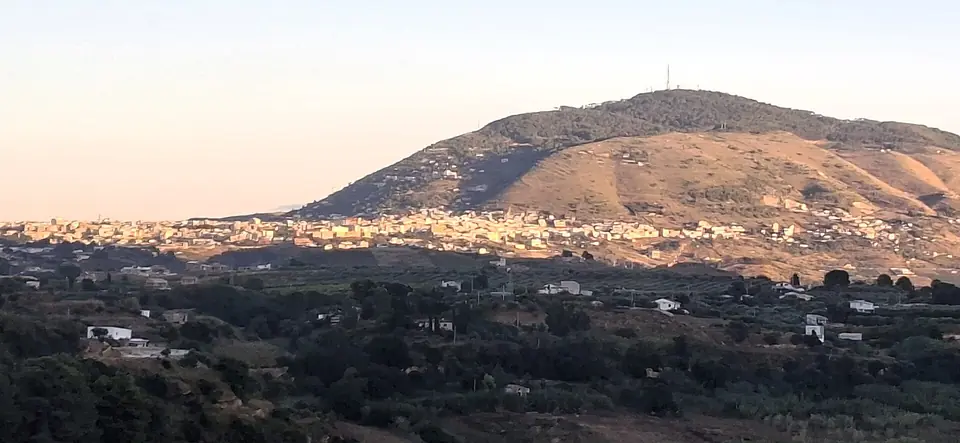 Bebyggelse vid Alcamo med berg bakom i varmt ljus