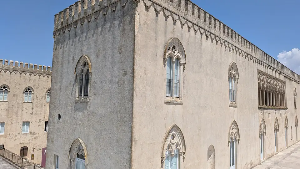 Ljus slottsfasad med spetsbågiga fönster vid Donnafugata