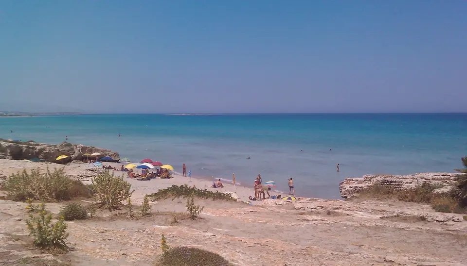 Ljus strand, klippor och badande vid San Lorenzo nära Noto