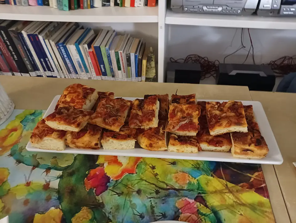 Bitar av tjock sfincione med tomattopping på ett serveringsfat
